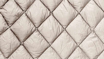 Obraz premium Quilted fabric in neutral color displayed on a flat surface for review by a textile enthusiast or designer