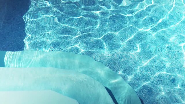 The clear water in the pool gleams and reflects the rays of the sun on a summer day