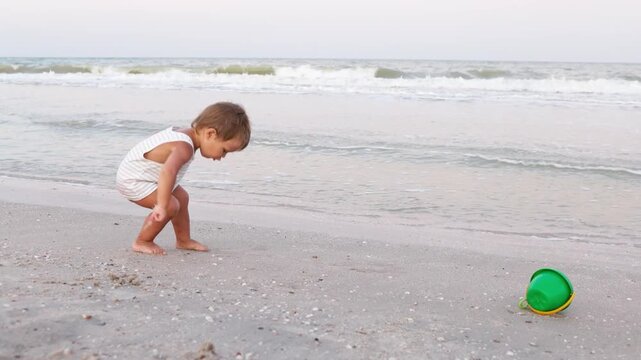 Kid collects shells and pebbles in the sea on a sandy bottom under the summer sun on a vacation
