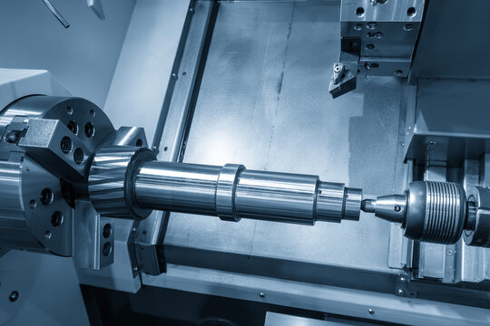 High-precision finishing process of a metal component on a CNC lathe machine utilizing a tailstock for rigid support in a light blue scene.