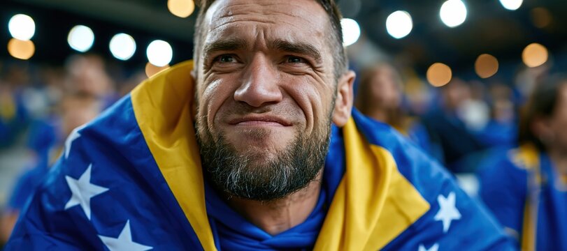Bosnian football supporter wrapped in national flag at stadium