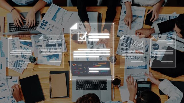 A group of diverse professionals collaborates on business strategies during a meeting. They analyze reports and data visualizations while utilizing technology and teamwork. Raster