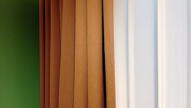 Close-up detail of elegant brown blackout curtains combined with soft white sheer curtains in a modern interior setting. Minimalist home decor concept featuring fabric texture, vertical folds, and nat