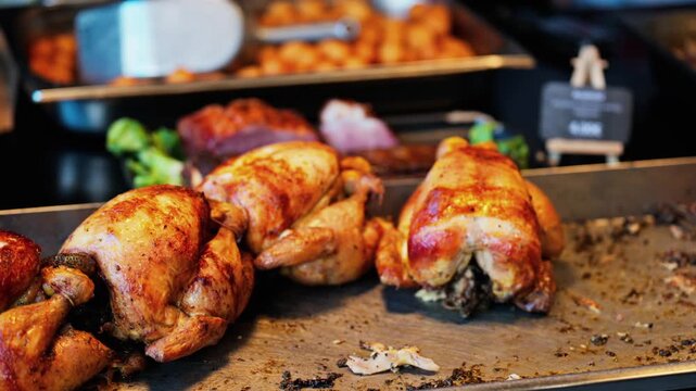 Whole roasted chickens on metal tray at european street food market stall with golden crispy texture.