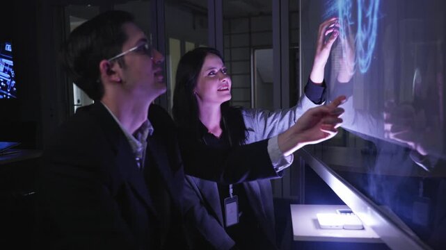 A professional man interacts with a high-tech circular data interface on a large digital screen, featuring graphs and data elements in a glowing blue theme.