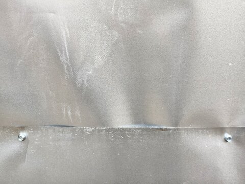 ​Industrial galvanized steel sheets overlap joint with hex screws, dented zinc metal plate background with scratches.
