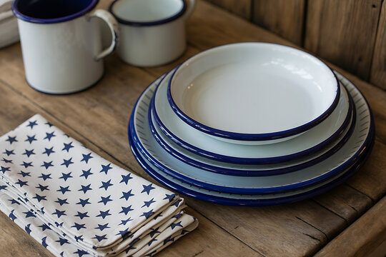 Stack of white and blue enamel plates with matching mugs and napkin food service serving dish table linen enamelware domestic
