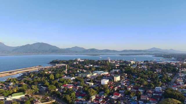 Aerial view of Puerto Princesa coastal city in Palawan with bay waterfront homes mountains islands and clear sunrise sky