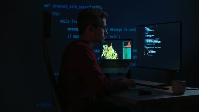 Data scientist writing code for artificial intelligence project, with programming scripts visible across desktop monitors. Coder in glasses working in front multiple screens at night. Copy space