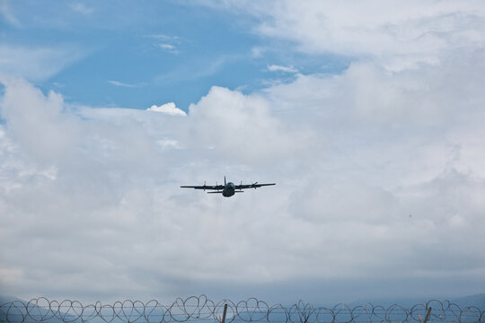 Four-Engine Turboprop Military Transport Aircraft Taking Off into Blue Sky with Clouds