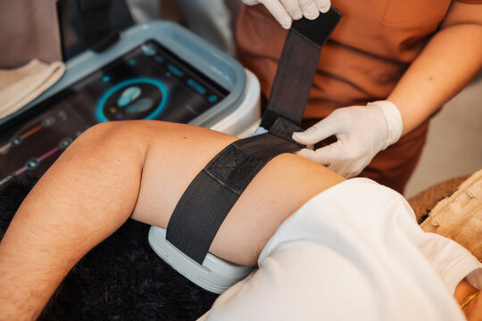 Middle aged male client receiving electromagnetic muscle stimulation treatment on the arm for toning and body sculpting in an aesthetic clinic.