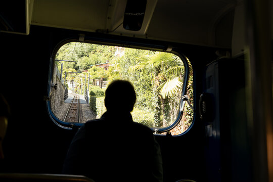 Man driving a blue funicular railway uphill with a Swiss flag visible along the route. Scenic mountain transportation in the Swiss Alps with beautiful alpine surroundings.