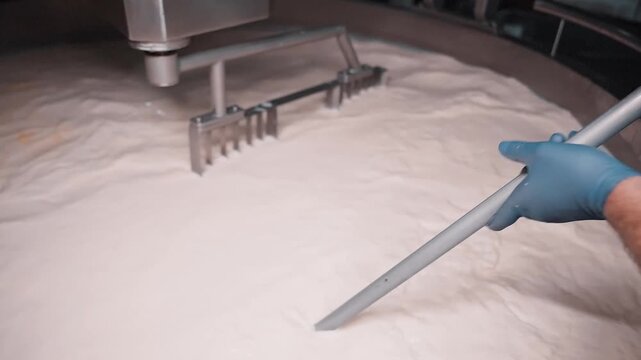 4k close up footage of mechanic arms mixing hot milk at the dairy factory. closeup of wire frames rotating in automated heating vat at cheese plant, cutting yellow mass into pieces and separating it f