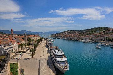 Elevated panoramic view of the Trogir waterfront promenade with palm trees, historic old town architecture, and yachts moored in the azure sea, Croatia © Ewa Bogucka