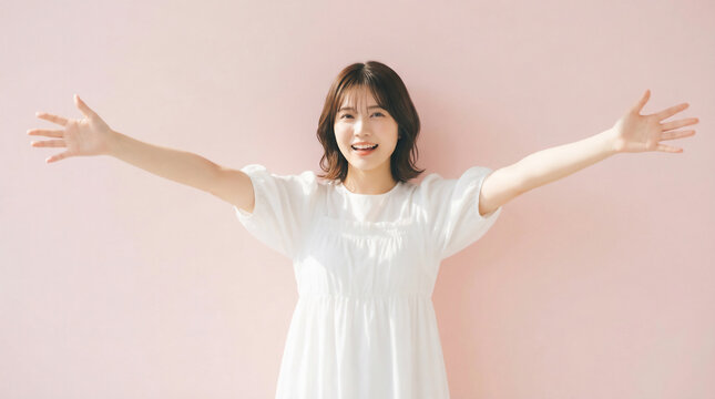 Cheerful Japanese woman opening her arms wide for a warm welcome on a pink background