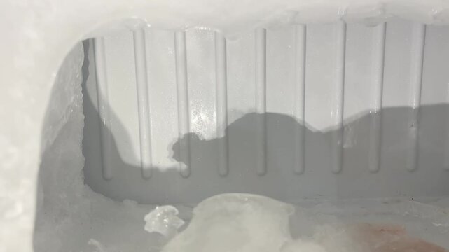 excessive ice buildup melting inside an old refrigerator freezer compartment. Household appliance problem concept showing overfreezing, frost accumulation, maintenance and energy efficiency issue