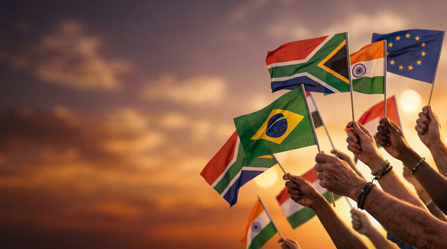 Diverse group of hands waving colorful flags against a vibrant sunset sky, symbolizing unity and celebration, with warm, glowing light in the background