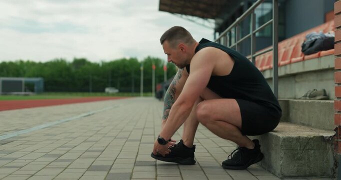 Sportsman lacing up sneakers on bleachers and going to start an outdoor workout