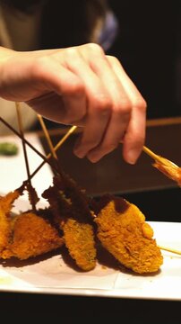 揚げたての串揚げ(串カツ)にタレを絡める美味しそうな瞬間の縦型動画