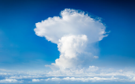 Large cumulus cloud rises into blue sky. Powerful cumulonimbus cloud formation showcases vertical development within bright blue sky. Weather forecast concept
