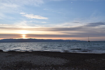 Obraz premium sunset over the sea with sailboats and mountain silhouette Poetto