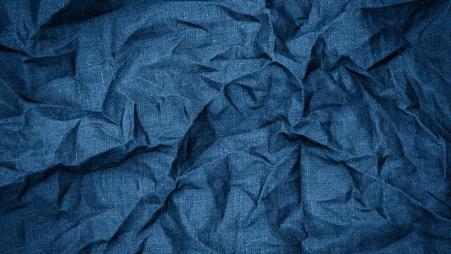 Crumpled blue fabric shows texture and pattern with wrinkles and folds in natural light setting