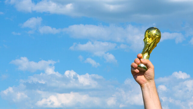 Moscow, Russia - May 22, 2026: FIFA World Cup Trophy in male hand сelebrating the victory against blue sky with clouds