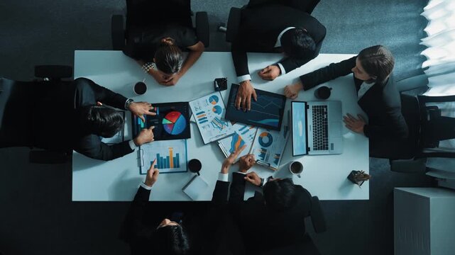Top down aerial view of professional businessman handed out financial statistic to analyst data investment graph. Group of diverse investors brainstorming and planning marketing strategy. Directorate.