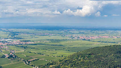 Obraz premium Vineyards and fields stretch over the landscape with distant mountains and clouds in the sky during daytime
