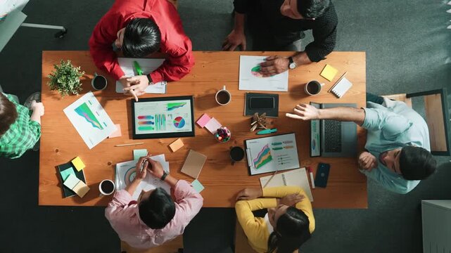 Top view of businesswoman sharing idea while stand at white board while manager asking question at table with tablet display financial graph. Attractive female leader pointing at board. Convocation.