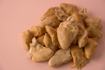 Fototapeta premium Close-up of premium freeze-dried chicken heart pet treats piled on a pastel pink background. Healthy, natural, and dehydrated raw meat dog and cat food. Minimalist studio shot of animal nutrition.
