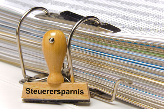 Ein Holzstempel ist bedruckt mit der Aufschrift: Steuerersparnis