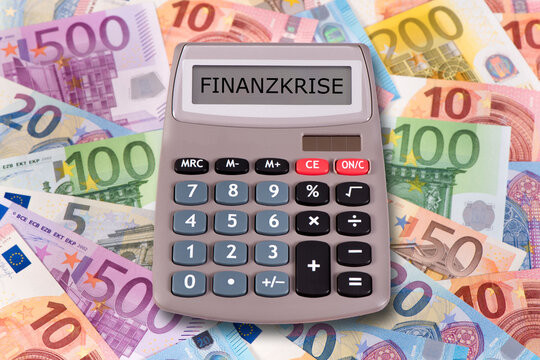 Auf vielen Euroscheinen liegt ein Taschenrechner mit dem Wort Finanzkrise im Display - FOTOMONTAGE