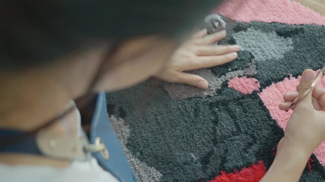 A close-up view of hands working on vibrant textile art, showcasing creativity and craftsmanship. The intricate patterns and colors reflect the beauty of handmade artistry.