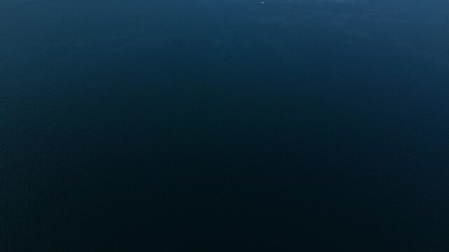 Aerial view captures vast ocean under clear sky. Calm scene appeals to nature lovers.