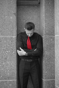 Depressed black and white businessman with red tie in stone niche with copy space