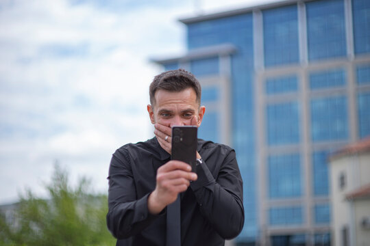 Stunned executive staring at mobile phone screen with blue office background with copy space