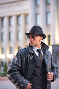 Dynamic private detective in sunglasses walking by government columns with copy space