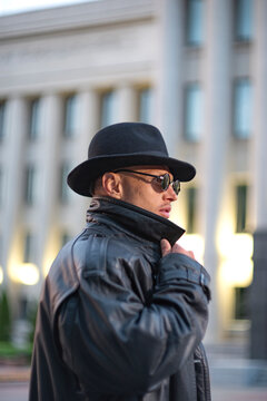 Secret agent in sunglasses adjusting leather coat collar with copy space
