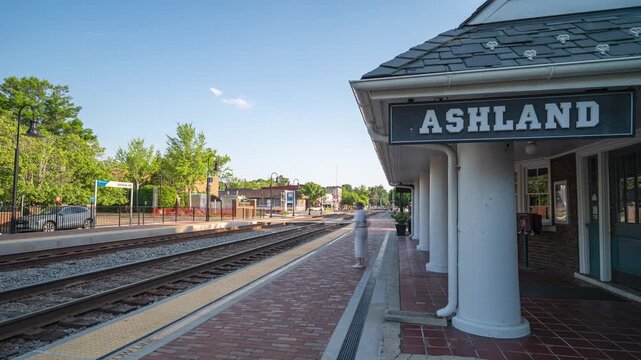 Ashland, Virginia, 4K time-lapse video looking down the railroad tracks next to the historic passenger train station platform and sign as light shifts across the downtown district.