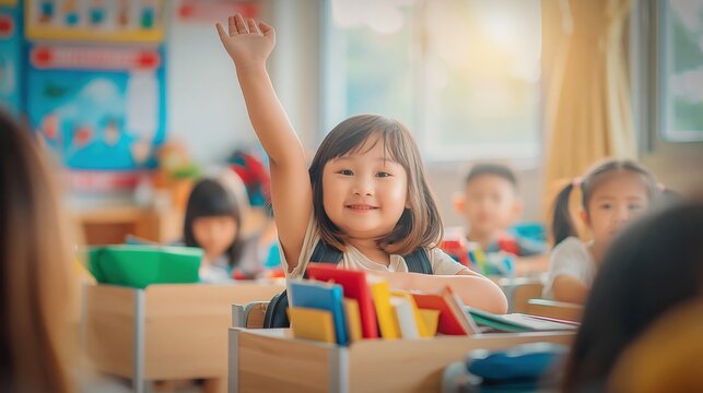 Happy Asian schoolgirl raising hand enthusiastically in a bright, sunlit classroom environment