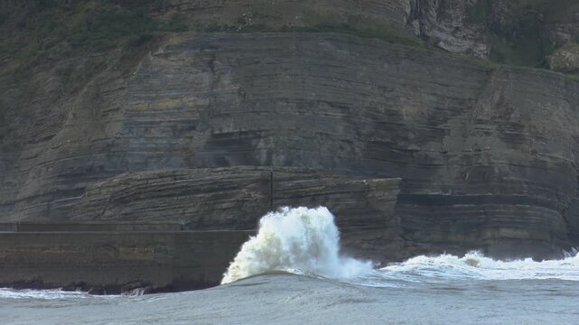 Plencia, spain; october 12 2022: large ocean waves crashing against a concrete breakwater