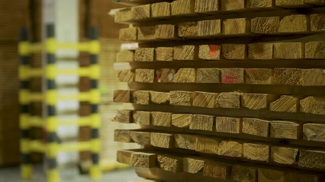 A stack of solid wood planks professionally arranged with spacers on a factory floor. This preparation is essential for air circulation during the kiln drying process in a woodworking facility