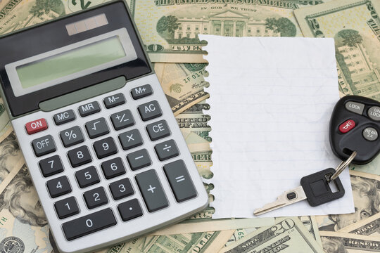 Calculator with torn blank paper and car keys on twenty dollar bills for cost of insurance