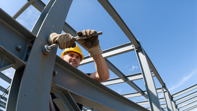 Construction worker installing steel beam on building site. Professional builder in hard hat working on metal structure