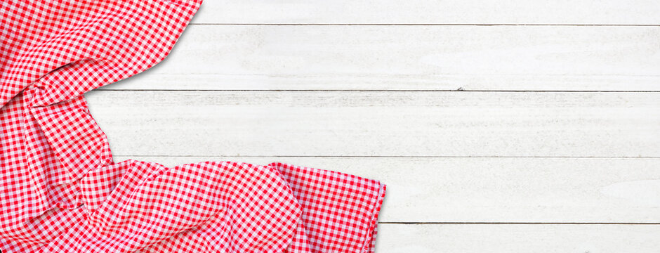 Picnic theme white wood background with red and white check cloth corner border. Top view banner. Copy space.