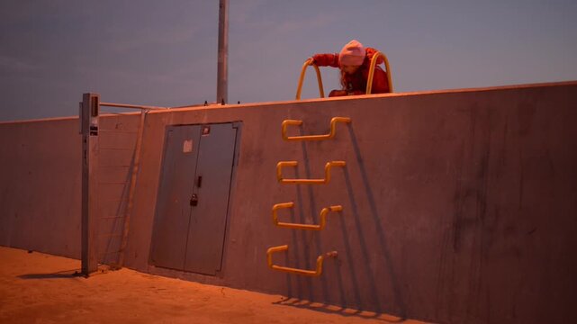 Two little girls climbed metal stairs by wall