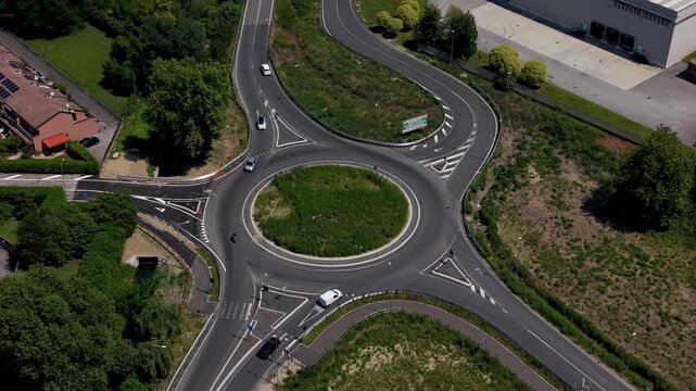 Roundabout Junction Aerial View: An aerial perspective of a busy roundabout junction with cars navigating the lanes amidst green surroundings.