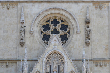 Obraz premium Detailed architectural view of the stone facade of Zagreb Cathedral featuring a large Gothic rose window and detailed religious sculptures in Croatia
