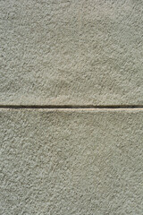 Fototapeta premium A close up background texture of a rough grey plaster building wall divided by a deep horizontal groove
